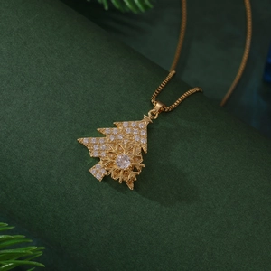 Gold Christmas tree and snowflake necklace with zircons on festive pine background