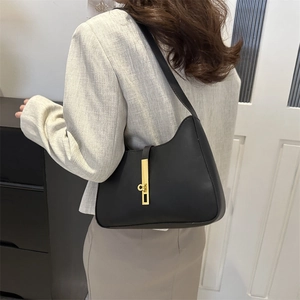 Minimalist black crescent leather underarm bag with gold metal buckle on female model