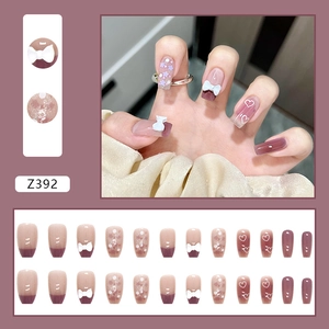 Détail de faux ongles rose dégradé avec nœuds 3D blancs et motifs floraux