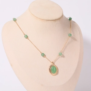 Dettaglio del ciondolo vintage con pietra verde e filigrana dorata sulla collana
