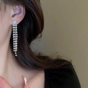 Close-up of long silver tassel earrings with multiple rows of sparkling rhinestones