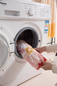 Close-up of machine washable floral bathroom mat being placed in a washing machine