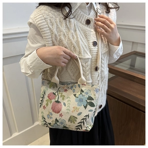 Detailed close-up of a floral jacquard bucket bag with strawberry patterns and a long strap