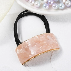 Detail of pink marble acetate hair tie with elegant gold trim and black elastic rope