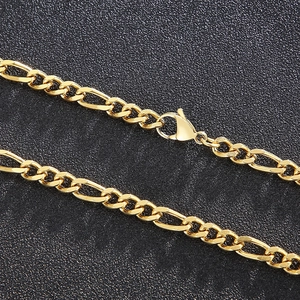 Close-up of golden Figaro chain necklace featuring a secure lobster clasp on black background