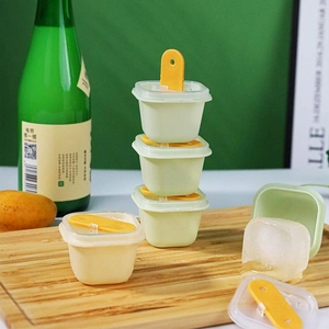Stackable popsicle molds with lid on a wooden board featuring a creative green design
