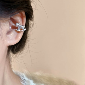 Close-up of a silver rocking horse ear cuff with zircons worn on a model's ear