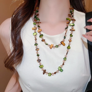 Detail of bohemian double-layered beaded necklace with natural green and amber stones