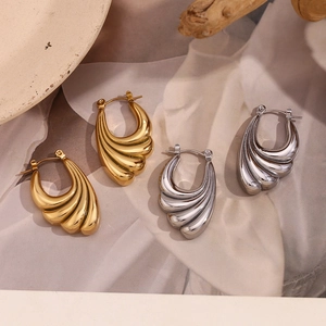 Macro detail of 18K gold and silver hoop earrings with a wave pattern on textured fabric