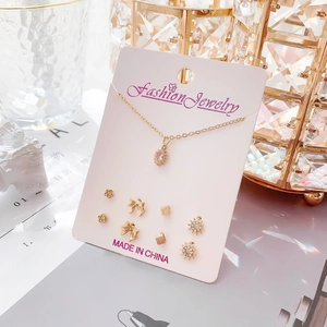 Détail du collier doré avec pendentif cristal et divers clous d'oreilles fleuris