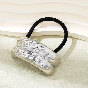 Detail of silver hammered metal ornament on elastic black hair tie for ponytail