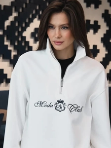 Detail of white half-zip sweatshirt featuring black Moda Club logo print and stand collar