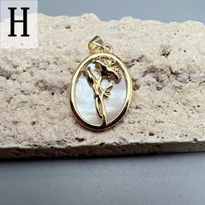 Macro shot of oval shell flower pendant with gold hollow floral design and pearl finish