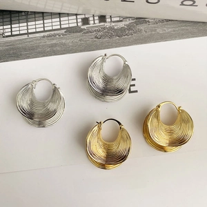Detailed view of layered threaded texture on gold and silver chunky hoop earrings