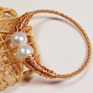 Detailed close-up of handmade double freshwater pearl gold wire-wrapped open cuff bracelet