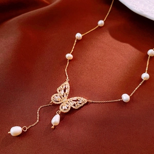 Macro detail of gold butterfly necklace featuring cubic zirconia and freshwater pearls