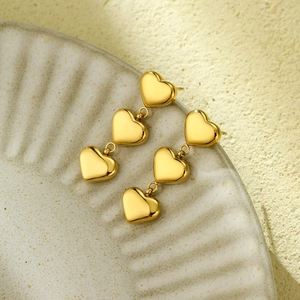 Detailed view of 18K gold plated stainless steel heart earrings on a ceramic dish