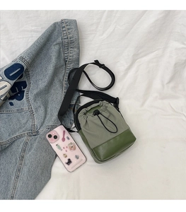 Detail view of mini crossbody bag with drawstring closure and phone for scale