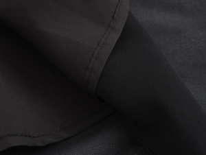 Detailed macro view of black chiffon fabric texture with elegant pleats and stitching