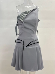 Détail de la robe grise plissée avec fermeture éclair asymétrique et boucles noires