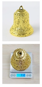 Detail view of 10cm gold Christmas bell with scroll relief showing 31.2g weight on scale