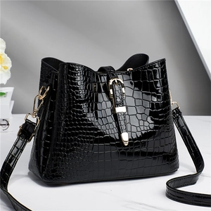 Elegant black crocodile pattern tote bag with gold hardware and adjustable strap on marble