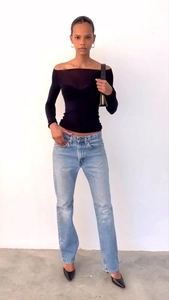 Détail d'un haut noir à épaules dénudées assorti d'un jean en denim bleu clair chic