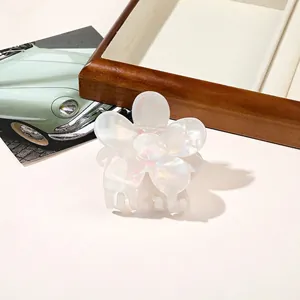 Macro shot of white iridescent flower hair claw clip with pearl finish on wooden tray