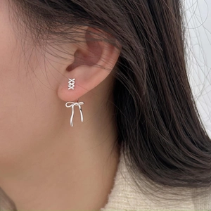 Detailed close-up of 925 sterling silver bow and cross stud earrings on female model