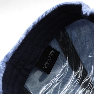 Detail view of denim octagonal hat interior showing 100% cotton label and inner sweatband