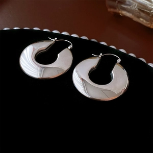 Macro view of chunky silver-tone stainless steel hoop earrings on a velvet display