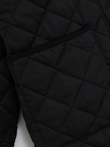 Detailansicht der Rautensteppung und Taschenpaspelierung an der schwarzen Nylonjacke