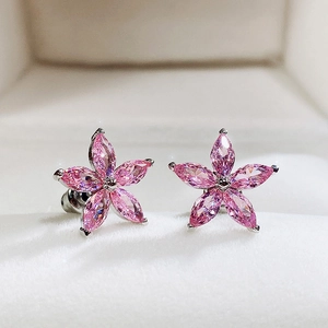 Macro shot of pink flower stud earrings with five petal-shaped gemstones in silver setting
