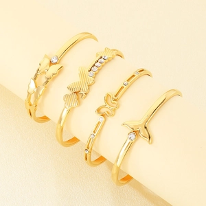 Vista dettagliata di quattro bracciali rigidi placcati oro 18K con farfalle e coda.