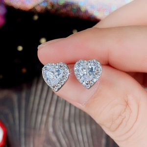 Close-up of heart-shaped zircon earrings in silver setting with halo diamond detail