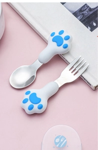 Macro detail of 304 stainless steel cutlery set with blue paw print handles on pink backdrop