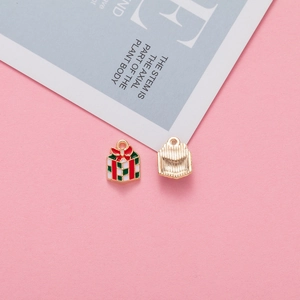 Detailed close-up of a Christmas gift box charm with red and green enamel on a gold base