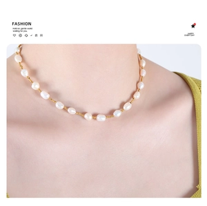 Detail of freshwater pearl necklace with gold steel beads worn by a model in soft light