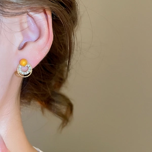 Close-up of elegant gold earrings with yellow cat eye stone and rhinestone circles