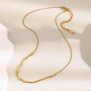 Macro detail of 18K gold-plated beaded tube chain necklace with K18 engraved tag