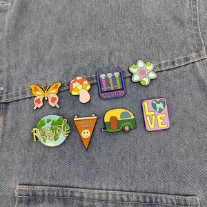 Set of 8 eco-friendly enamel pins with earth, butterfly and camping designs on denim
