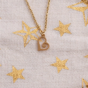 Golden titanium steel necklace with a spiral heart pendant on a starry fabric backdrop