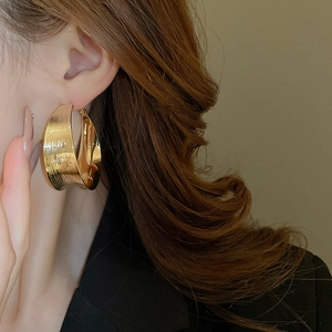 Golden textured hoop earrings with brushed metal finish shown on a side profile model