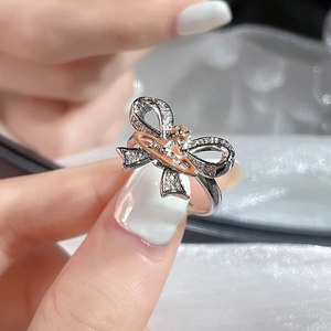 Elegant silver bow ring featuring a sparkling Saturn cross design on a model finger