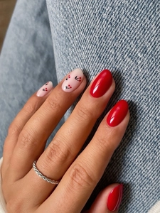 Macro shot of long red and nude press-on nails with cherry patterns and glitter