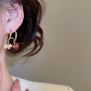 Detail of gold plated Scottie dog earrings with red heart charms worn by a model