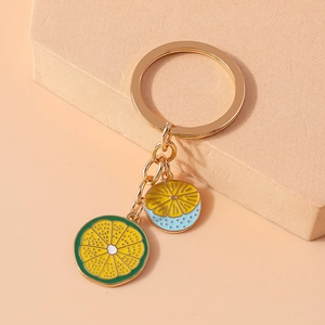 Detailed macro view of enamel lemon and lime slice charms on a gold metal keychain
