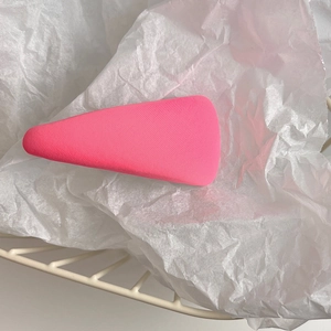 Detailed view of a pink matte triangle hair clip on textured white paper background