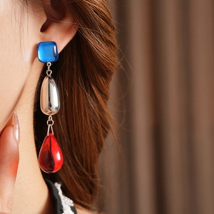Close-up of vintage tassel earrings with blue square and red teardrop resin charms
