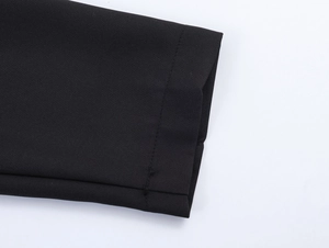 Vue macro détaillée montrant les coutures et l'ourlet du tissu noir de la robe blazer
